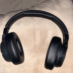 JBL Over-Ear Wireless Headphones - Som nya Snygga svarta JBL over-ear hörlurar med trådlös anslutning. Mjuka öronkuddar och tydliga knappar för enkel kontroll. Hörlurarna är i mycket gott skick utan synligt slitage eller defekter. Perfekt för musik, film och samtal med hög komfort och bra ljudkvalitet.