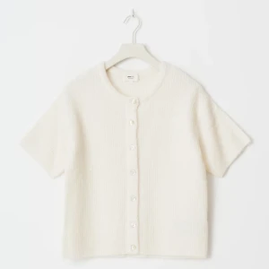 Vit kortärmad kofta från Gina Tricot - Superfin vit kofta med korta ärmar från Gina Tricot. Den är stickad i mjukt material och har rund hals samt knappar framtill. Perfekt att styla med jeans eller kjol för en clean och fräsch look. Enkel och tidlös design som passar till många outfits. Helt ny och aldrig använd