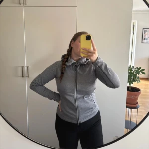 Grå hoodie med dragkedja och huva - Säljer en grå hoodie med hel dragkedja och praktisk huva med snörning. Tröjan har två fickor med dragkedja och är långärmad. Snygg och enkel design som funkar till det mesta.