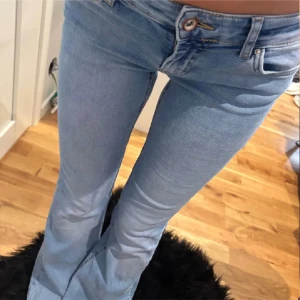 Bootcut ljusblå jeans med låg midja - Snygga ljusblå bootcut jeans med låg midja och klassisk femficksdesign. Jeansen har en smal passform över låren och blir vidare nedtill, vilket ger en riktigt chill siluett. Tillverkade i mjukt denimtyg med knapp och dragkedja framtill.