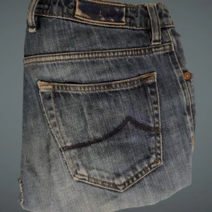 Jacob Cohëns jeans med blå färg  - Snygga Jacob Cohën med en skada som är lagad och man inte tänker på när man ser dem. Blå jeans med päls där bak vid fickan. 