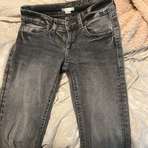 Grå jeans med broderad bakficka - Snygga grå jeans från Gina Tricot med coolt broderi och paljettdetaljer på bakfickan. Modellen har klassisk femficksdesign, raka ben och normal passform. Jeansen är tillverkade i mjukt bomullsmaterial med en tvättad look.