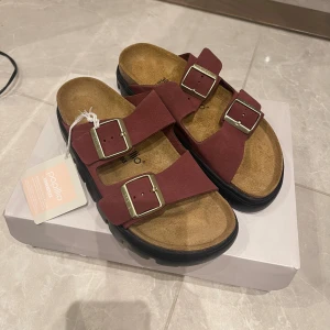  Birkenstock sandaler vinröd - Chunky sandaler från Papillio by Birkenstock i vinröd mocka med två breda remmar och stora metallspännen. Storlek 38, helt nya med prislapp