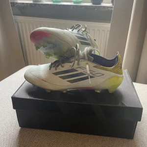 Adidas F50 fotbollsskor vit/gul - Säljer ett par Adidas F50 Elite FG/AG. Skorna är hela och i bra skick. Medföljer skopåse.
