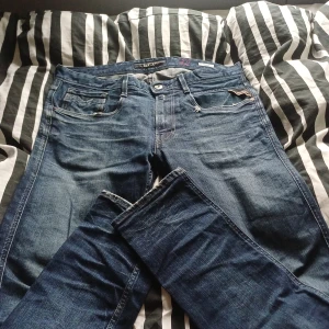 Blå Replay Anbass jeans, storlek 32 - Säljer ett par snygga blå Replay Anbass jeans i klassisk femficksmodell. Jeansen har en normal passform och är tillverkade i slitstarkt denim med snygga detaljer på fickorna. Perfekta för dig som gillar stilrena och tidlösa jeans.