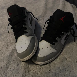 Air Jordan 1 Low Light Smoke Grey - Säljer ett par Air Jordan 1 Low Light Smoke Grey i grått, vitt och svart med klassisk röd Jumpman-logga på plösen. De har kommit till användning Max 4 gånger och är i stolek 38!