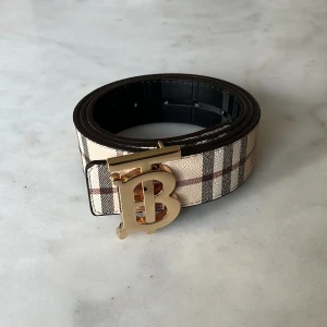 Vändbart burberry bälte - fett vändbart bälte från burberry med guldspänne i storlek 95/110cm, hålgörare ingår. Oanvänt skick och fraktas inom 24h✅