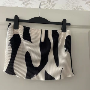 Plisserad svartvit zebramönstrad Tubtopp  - Superfin kort plisserad Tubtopp med zebramönster i svart och vitt. Tubtoppen har elastisk midja och är gjord i ett lätt, syntetiskt material som ger ett snyggt fall. Perfekt för dig som vill sticka ut med en trendig och cool look.