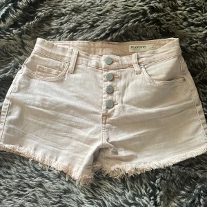 Ljusbeigerosa jeansshorts från BLANKNYC - Säljer ett par ljusbeigerosa midwaist jeansshorts från BLANKNYC. De har fransig kant nertill, fyra silverknappar framtill och klassiska fickor både fram och bak. Perfekta för sommardagar och riktigt snygga till sneakers eller sandaler.