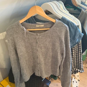 Grå kofta från Gina Tricot XL - Mysig grå kofta från Gina Tricot i storlek XL. Koftan är stickad och har rund hals, långa ärmar och knappar framtill. Perfekt för lager-på-lager och chill dagar. Enkel och stilren design som funkar till jeans eller kjol.