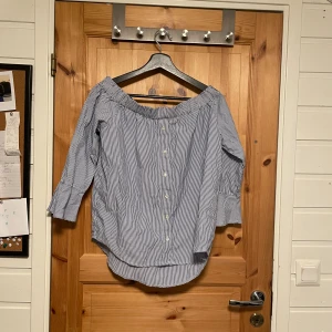 Randig off the shoulder topp i skjortmaterial - Säljer en Randig off the shoulder topp i skjortmaterial från AMISU i storlek S.