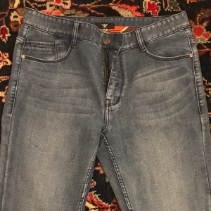 Armani Jeans slim fit blå denim - Snygga blå jeans från Armani Jeans i slim fit-modell. Klassisk femficksdesign med diskret logga på bakfickan och coola detaljer på insidan av linningen. Jeansen har dragkedja och knapp framtill och är tillverkade i mjuk denim.