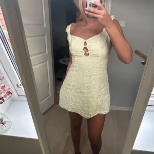Ljusgul kort klänning med broderade blommor från asos - Supersöt ljusgul kort klänning med broderade blommor och pärlknappar framtill. Klänningen har smickrande passform, ärmlös design med små axelband och fina cut-outs vid bysten. Perfekt för varma dagar och somriga vibes! Från asos i storlek s💕