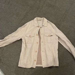 Beige overshirt från MNG Man, M - Säljer en stilren beige overshirt från MNG Man i storlek M. Jackan har två bröstfickor med lock och knappar framtill. Perfekt för lager-på-lager och har en clean look med klassisk krage och långa ärmar.