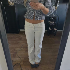 Vita raka jeans med låg midja - Säljer ett par vita jeans med låg midja och raka ben. Byxorna har klassisk femficksdesign och stängs med knapp och dragkedja. Perfekta för dig som gillar en clean och stilren look. Passar till allt och är superenkla att styla.