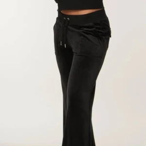 Juicy byxor med fickor - Svarta mjukisbyxor i mjuk sammet med bred resår i midjan och snörning framtill. Byxorna har bootcut, stora fickor fram och bak samt diskret logga på ena fickan. Perfekta för en chill och avslappnad look.