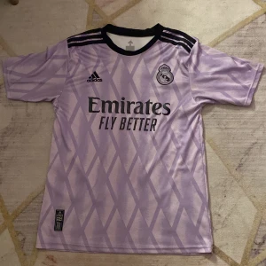 Real Madrid Vini Jr. bortatröja lila - Säljer en lila Real Madrid bortatröja från Adidas med Vini Jr. och nummer 20 på ryggen. Pris kan diskuteras vid köp 