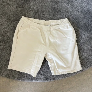 Beiga mjuka shorts med resårmidja - Säljer ett par beiga shorts i mjukt material med elastisk midja och fickor på sidorna samt en bakficka. Perfekta för chill dagar eller när du vill ha det bekvämt. Klassisk och enkel design som funkar till det mesta.