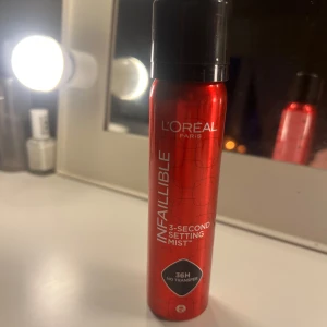 L'Oréal Infaillible Setting Mist - Endast textad en gång, L'Oréal Infaillible 3-Second Setting Mist i röd metallisk flaska. Ger makeupen en långvarig finish upp till 36 timmar utan att smeta av sig. Perfekt för att fixera sminket snabbt och enkelt. Sprayformat för smidig applicering.