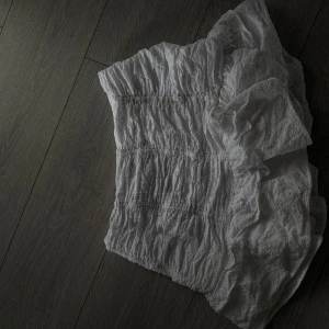 Vit volangkjol från Zara - Supersöt vit kortkjol från Zara med broderade detaljer och volangkant. Kjolen har smockad midja som ger en bekväm och snygg passform. Perfekt för sommarens alla tillfällen och lätt att matcha med crop tops eller linnen.