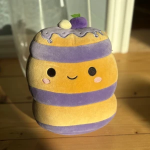 Squishmallow Paden the Blueberry Pancake - Squishmallow – Paden the Blueberry Pancake🫐 Perfekt för samlare eller som mysigt gosedjur! 	•	Storlek: 19 cm 	•	Skick: Som ny – inga fläckar, inte använd 	•	Har endast stått i fönsterkarmen 	•	Alla tags/lappar är tyvärr inte kvar  ✨ Pris: 100 kr ✨  Mjuk, squishig och redo för ett nytt hem!💜