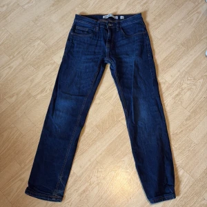 Mörkblå jeans från Indicode, 29/30 - Snygga mörkblå jeans från Indicode i klassisk femficksmodell. Jeansen har raka ben och normal passform, med kontrastsömmar och knappstängning. Perfekta till en avslappnad stil och funkar året runt.