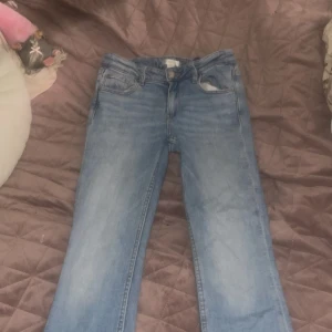 Ljusblå jeans från Gina Tricot, strl 152 - Snygga ljusblå jeans från Gina Tricot i klassisk femficksmodell. Jeansen har raka ben och normal passform, tillverkade i mjukt denimtyg. Perfekta för dig som gillar en enkel och stilren look. Bälteshällor och knappstängning framtill.