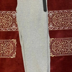 Grå mjukisbyxor från Nike, storlek M - Snygga grå mjukisbyxor från Nike i storlek M. Byxorna har dragsko i midjan, svarta detaljer och Nike-logga på vänster höft. Tillverkade i mjukt bomullsmaterial för maximal komfort. Perfekta för chill eller träning.