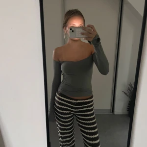 Grå offshoulder långärmad topp - Säljer en stilren grå offshoulder topp med lång ärm och tight passform. Toppen har en snygg asymmetrisk skärning över axlarna och är tillverkad i ett stretchigt, mjukt material som sitter skönt mot kroppen. Perfekt för dig som gillar minimalistisk och trendig stil.