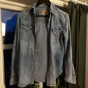 Jeansskjorta från Polo Ralph Lauren - Säljer denna grymt snygga blå jeansskjortan från Polo Ralph Lauren. Riktigt snygga detaljer. Materialet är mjuk bomullsdenim. Storlek S och passformen är slim fit. Mycket bra skick, hör av er vid minsta fråga!