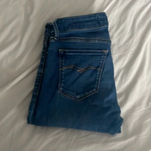 Blå skinny jeans från Replay - Säljer ett par blå skinny jeans från Replay med klassisk femficksdesign och snygga detaljer på bakfickan. Jeansen har en smal passform och är tillverkade i stretchigt denimtyg för extra komfort. Perfekta för dig som gillar en stilren och modern look. W28 L30 öppen för frågor priset går att diskutera.