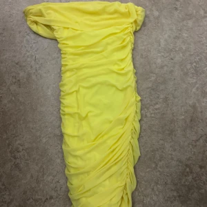 Gul  kortklänning - Superfin gul  klänning med snygga rynkade detaljer längs hela klänningen. Modellen är figurnära och kort, perfekt för dig som vill sticka ut. Materialet känns mjukt och följsamt mot kroppen.