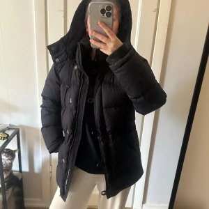 Mörkblå bolmerang jacka med huva och knappar - Säljer min finaste vinterjacka från boomerang. Köptes för typ 6000kr för några år sedan. Denna är så skön och snygg på, man kan spänna i midjan också så man blir lite snatched😆håller värmen superbra!! Finns lite små skavanker och bilder på det kan skickas. Men lite nött i färgen på vissa ställen, inget som märks om man inte kollar noga.(nacke, fickor, arm) säljer då jag ska köpa en annan vinterjacka💗💗💗