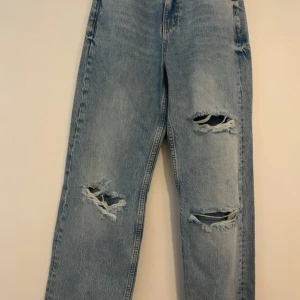  ripped jeans straight fit - Jeans från Gina Tricot – aldrig använda! Säljer dessa snygga ljusblå jeans från Gina Tricot. Storlek 32, men de är stora i storleken (mer som en 34). Om man har lite större lår, som jag, sitter de bra upptill vid låren – annars blir passformen mer oversized. Jeansen har slitna detaljer framtill för en trendig och avslappnad look. Aldrig använda, i nyskick! Pris kan diskuteras