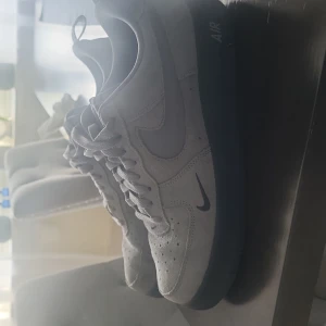 Nike Air Force 1 i grå mocka - Säljer ett par Nike Air Force 1 sneakers i grå mocka med svart sula. Klassisk siluett med rund tå, snörning och diskret Nike-logga på sidan och hälen. Perfekta för dig som gillar stilrena och tidlösa sneakers med en twist av mocka.
