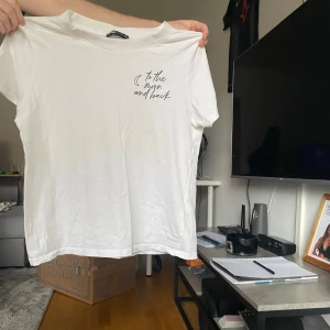 Vit t-shirt med texttryck - Vit t-shirt från Gina Tricot med korta ärmar och rund hals. På bröstet finns ett stilrent texttryck: 'to the moon and back' med en liten måne. Mjuk och skön bomullskvalitet, perfekt för en chill look.