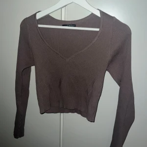 Brun croppad ribbad topp med v-ringning - Säljer en brun croppad topp från Bershka med ribbad struktur och snygg v-ringning. Fint skick 