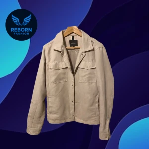 Beige overshirt - Stilren beige overshirt från Dressmann med klassisk krage, två bröstfickor med lock och tryckknappar framtill. Jackan är i mjuk mockaliknande syntet och har raka ärmar. Perfekt för lager-på-lager och enkel att matcha med det mesta. Används 3 gånger så nästan helt ny