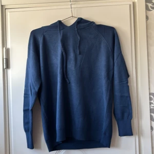 Blå stickad hoodie med huva - Mysig blå stickad hoodie med huva och dragsnören. Tröjan är helt ny asså aldrig använd verkligen för den var för liten och då tänkte jag sälja vidare den 