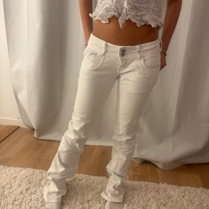 Vita bootcut jeans från Pepe Jeans - Snygga vita jeans från Pepe Jeans med bootcut passform och låg midja. Jeansen har dubbla knappar framtill, klassiska fickor och diskret logga bak på linningen. Perfekta för dig som vill ha en fräsch och stilren look.