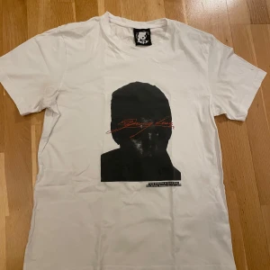 Yung Lean t-shirt med tryck - Stockholm 1 mars - Vit t-shirt från Yung Lean med svart siluett-tryck och röd text på bröstet. Trycket har en cool grafisk stil och det finns även en liten textdetalj på ryggen. Klassisk passform och rund hals. Inte använt så ofta så tänker sälja💔🫡