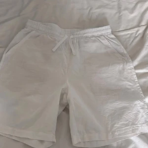 Vita shorts med snörning från grunt - Snygga vita shorts med elastisk midja och snörning framtill. De har en avslappnad passform och är tillverkade i ett lätt bomullstyg, perfekta för varma dagar. Fickor på sidorna och en bakficka ger en chill vibe.