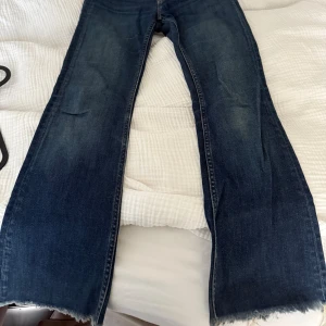 Crocker blå bootcut jeans low waist - Mörkblå jeans från Crocker Authentic jeans med bootcut passform och låg midja. Jeansen har råa, fransiga benslut och klassiska bakfickor. Materialet är en mix av bomull, polyester och elastan för extra stretch och komfort.