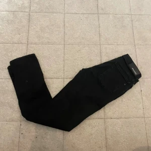 Svarta Replay jeans - Svarta jeans från Replay med klassisk femficksdesign och smal passform. Snyggt minimalistiska med svart patch bak i midjan. Perfekta till sneakers eller boots och funkar året runt.