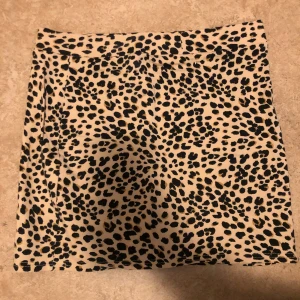 Leopardmönstrad kortkjol i beige - Snygg kortkjol med leopardmönster i beige och svarta toner. Kjolen har en rak passform och är perfekt för dig som vill sticka ut med en trendig look. Materialet känns mjukt och följsamt mot kroppen.