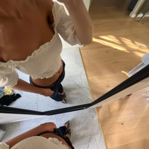 Vit offshoulder croppad blus - Superfin vit offshoulder blus med smockad kropp och volangdetaljer längs kanterna. Toppen har trekvartsärmar 