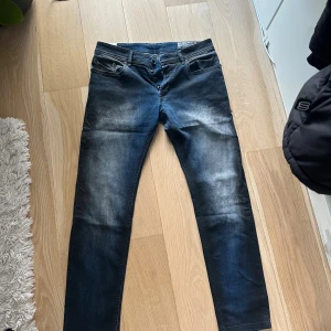 Mörkblå Diesel jeans med knappar - Snygga mörkblå jeans från Diesel med slitna detaljer och knäppning framtill. Modellen har smal passform och klassiska fem fickor. Jeansen har en cool tvätt och är perfekta för dig som gillar en modern look.