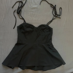 Svart korsett-topp med knytband - Säljs då den ej passar mig längre. Toppen är oanvänd, stängs och öppnas med dragkedja på sidan.