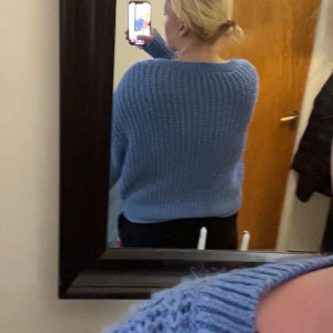 Blå stickad v-ringad tröja - Mysig blå stickad tröja med v-ringning och lång ärm. Tröjan har en loose passform och är perfekt för kyligare dagar. Den ribbade strukturen ger en snygg och avslappnad look.