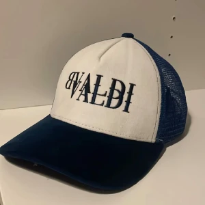Blå vit keps från BVALDI - Väldigt snygg keps från BVALDI med vit front och blått nät baktill, kepsen har böjd skärm i mörkblått och justerbar snapback. Broderad BVALDI-logga framtill ger en cool och modern look! Skick 10/10 som ny ✅Perfekt accessoar för att lyfta din stil till en ny nivå 💯